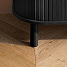 close up image of foot of black wooden fluted tv unit, on wooden floor