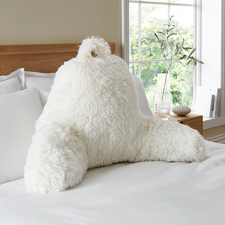 Cuddly shaggy faux fur chair cushion in cream on bed image 1