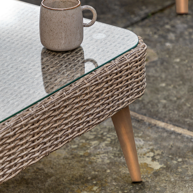 close up on glass-top of wicker table with acacia legs