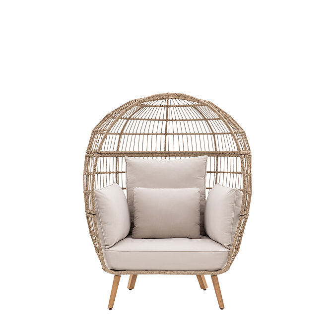 cut out of round wicker egg chair with plush cream cushions