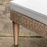close up image of wicker base of sun lounger with chic acacia wood legs