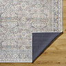 close up image of vintage rug with brown and blue shades, corner folded up to show material underneath