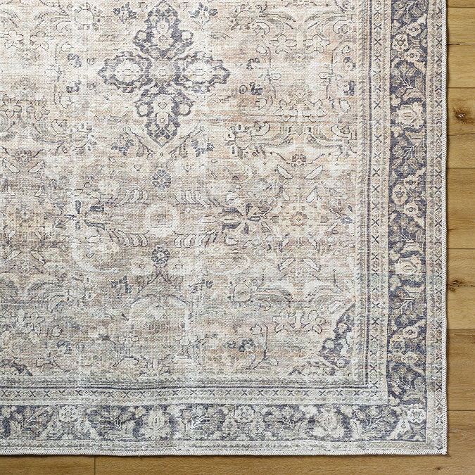 close up image of front of vintage rug with floral patterns in shades of grey, brown, and purple