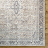 close up image of front of vintage rug with floral patterns in shades of grey, brown, and purple