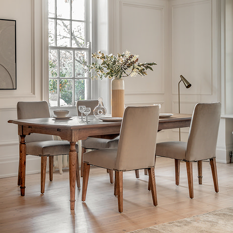 image of rectangular mindi wood dining table surrounded by upholstered velvet grey chairs, on wooden flooring of dining room