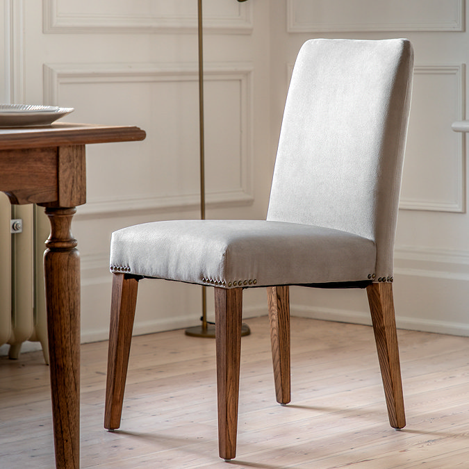 close up image of single velvet grey upholstered dining chair on wooden flooring of dining room