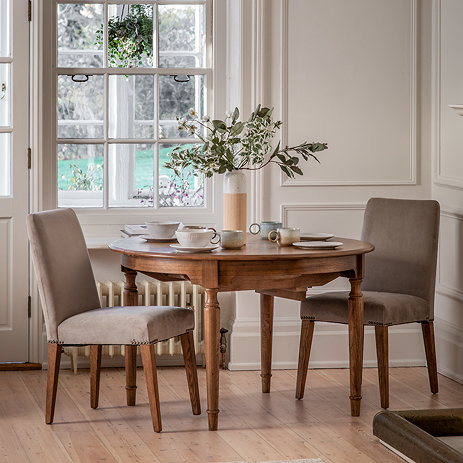 image of pair of velvet upholstered dining chairs tucked under mindi wood dining table