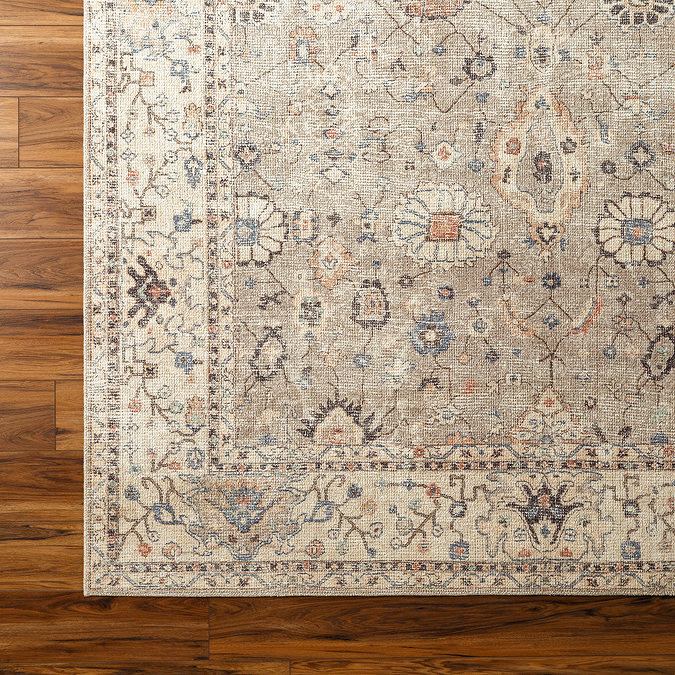 close up swatch image of brown floral vintage rug on dark wood flooring, focus on colour and texture