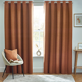 Dark orange floor length curtains over a living room window.