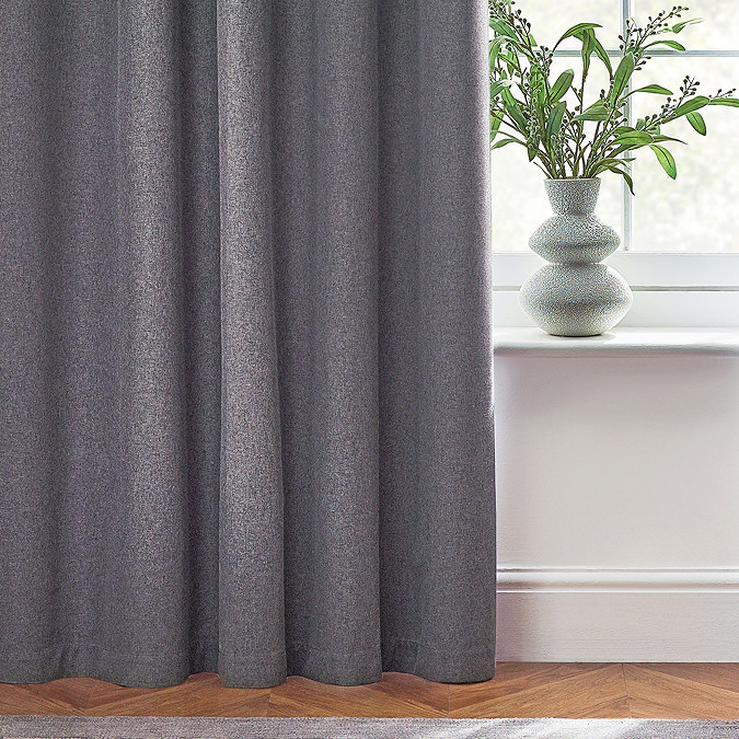 Close up on bottom of charcoal grey curtains brushing the wooden floor