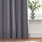 Close up on bottom of charcoal grey curtains brushing the wooden floor