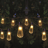 image of decorative warm white bulbs hanging between trees at night, emitting light