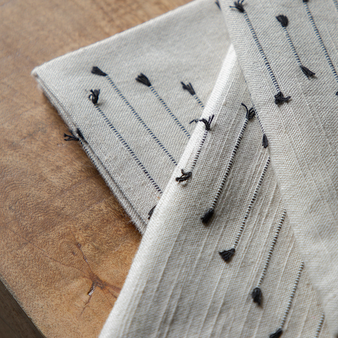 close up on embroidered pattern of linen napkin placed on a wooden table