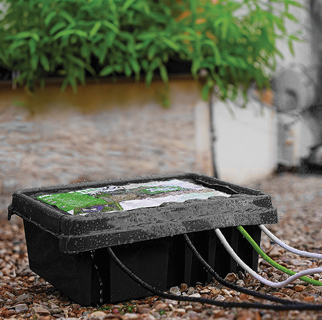 image of black rectangular electrical connection box on ground outside in rain