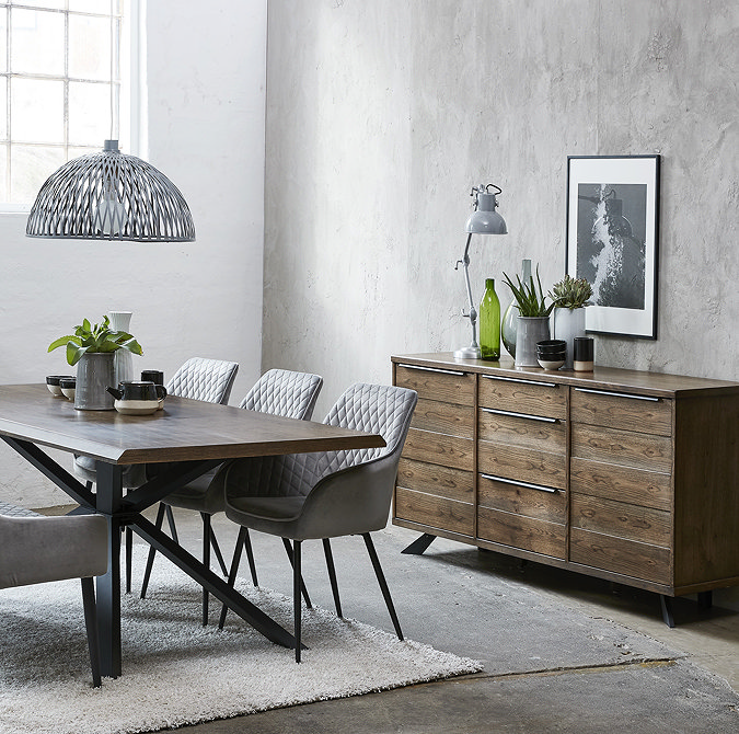 wide image of large panelled dark oak sideboard against a grey wall in dining room opposite large dining table and chairs