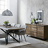 wide image of large panelled dark oak sideboard against a grey wall in dining room opposite large dining table and chairs