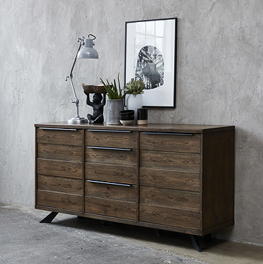 wide image of large panelled dark oak sideboard against a grey wall in dining room opposite large dining table and chairs