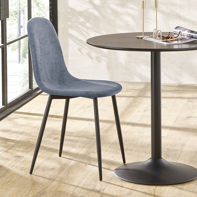 image of denim blue dining room chair tucked in next to black round table