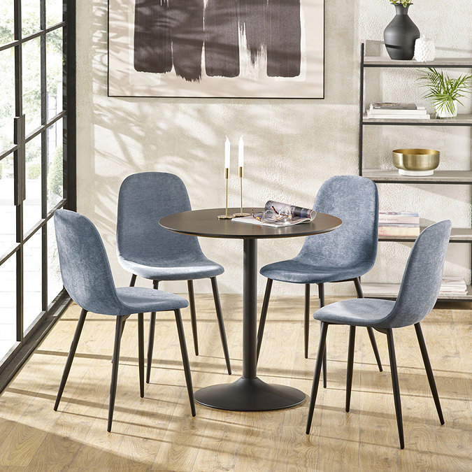 image of four denim blue chenille dining chairs with black metal legs round a black metal table on wooden flooring