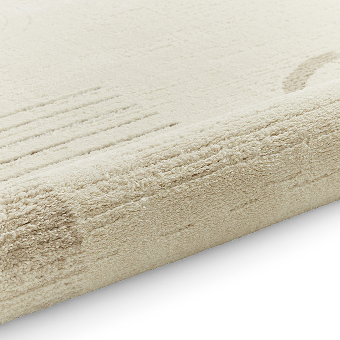 image of cream rug with beige abstract pattern rolled up at end