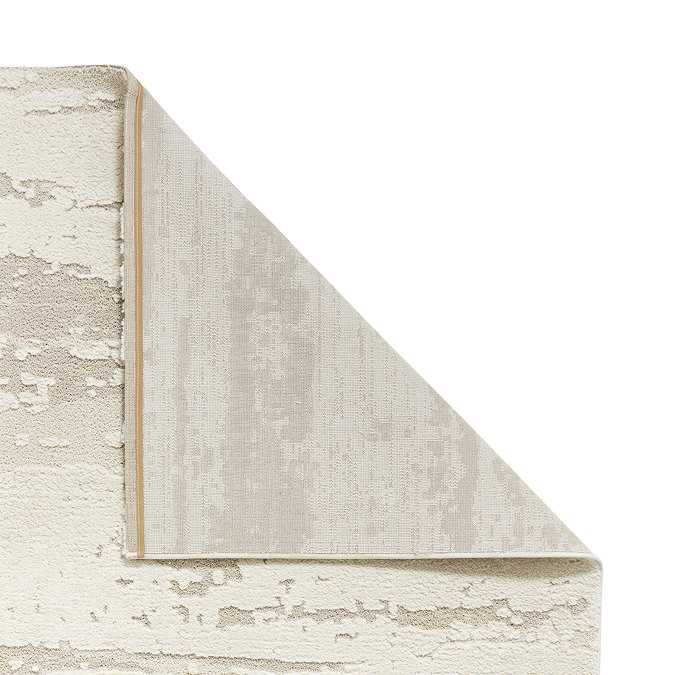 cream textured rug with corner folded over to show floor-facing material