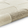image of beige and cream geometric rug rolled up at the end