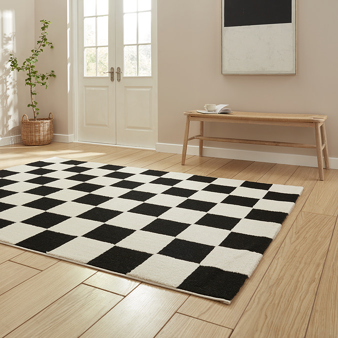 angled image of checkered black and white rug on light wooden floor