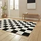 angled image of checkered black and white rug on light wooden floor