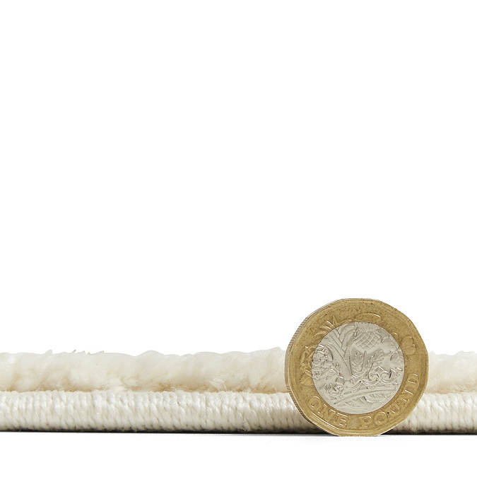 rug flat with pound coin stood up next to it to show height of rug as half the coin