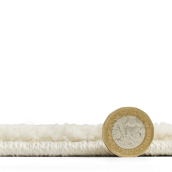 rug lying flat with pound coin stood up next to it to show rug as half the coin's height
