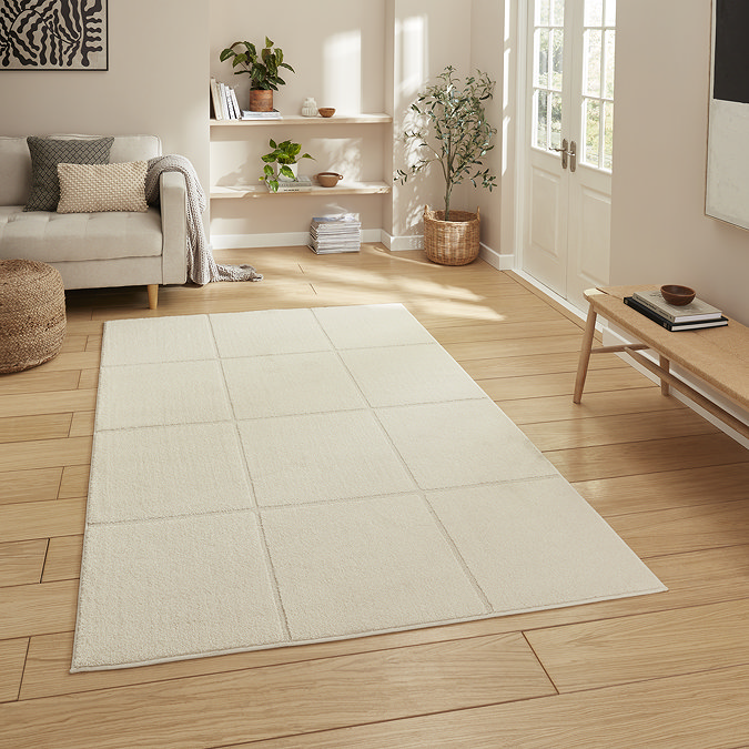 image of cream rectangular rug with clean line pattern, on light wooden flooring of modern loft apartment.