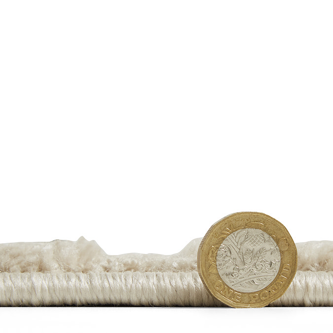 side on shot of flat rug with pound coin stood next to it to show rug as half the height of coin