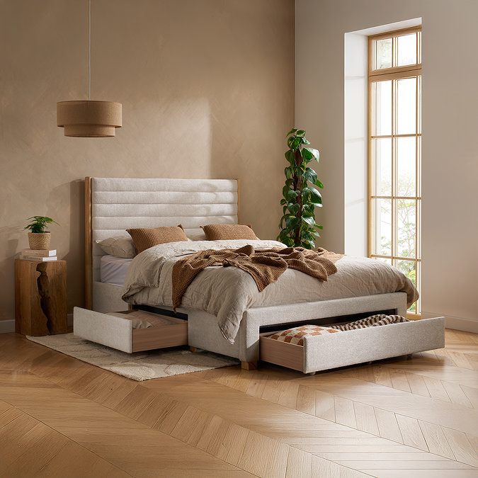 wide image of light grey velvet bed with front and side storage drawers open to show clothes stored inside