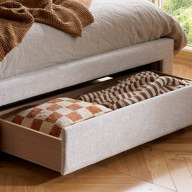 close up image on front drawer of bed pulled out to show cushion and throw stored inside