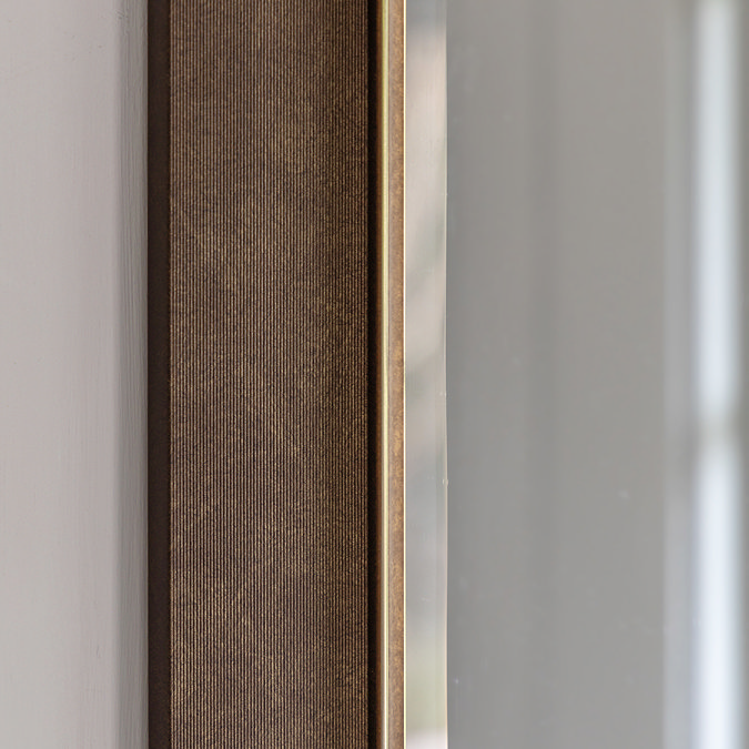 close up on bronze frame of rectangular wall mirror