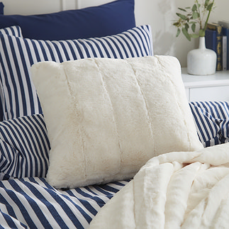 cream faux fur cushion on blue bedding