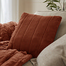 Rust coloured faux fur cushion on sofa