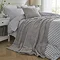grey faux fur throw draped over light blue striped bedding