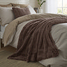 taupe brown faux fur throw draped over a bed