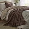 taupe brown faux fur throw draped over a bed