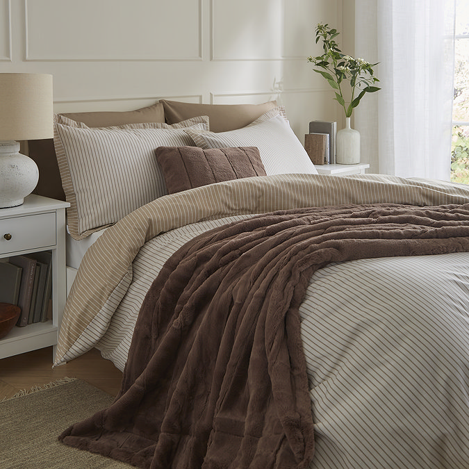 taupe brown faux fur throw draped over bed