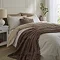 taupe brown faux fur throw draped over bed