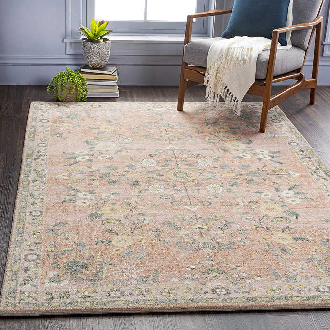image of soft pinky-orange rug with floral pattern on grey flooring