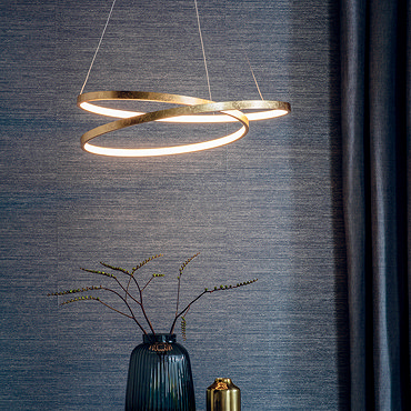 image of scribble-shape pendant light in gold, in front of dark grey wall