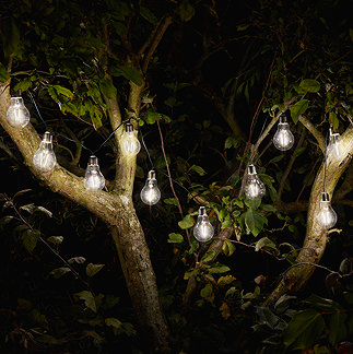 image of 10 retro bulbs emitting warm white light, hanging in tree at night