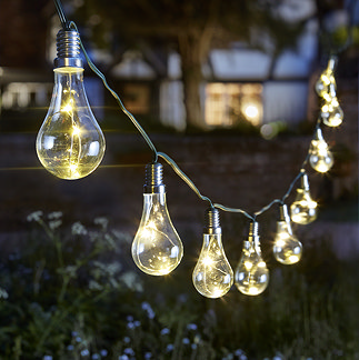 image of 10 string lightbulbs glowing warm light on string in front garden at night