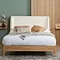 front on image of large wooden bed with white boucle headboard, dressed with mattress, sheets and cushions