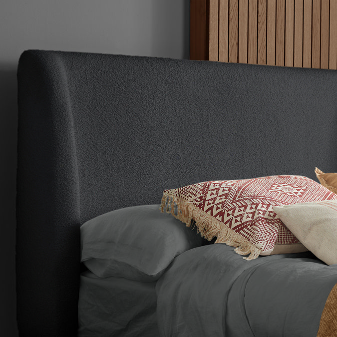 close up on grey boucle headboard with light orange accent cushion resting against it