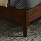 close up on walnut brown legs of evelyn bed on patterned rug