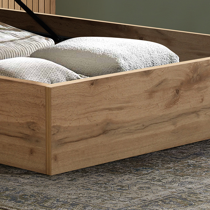 close up on oak frame of ottoman bed with storage compartment, clothes folded up inside